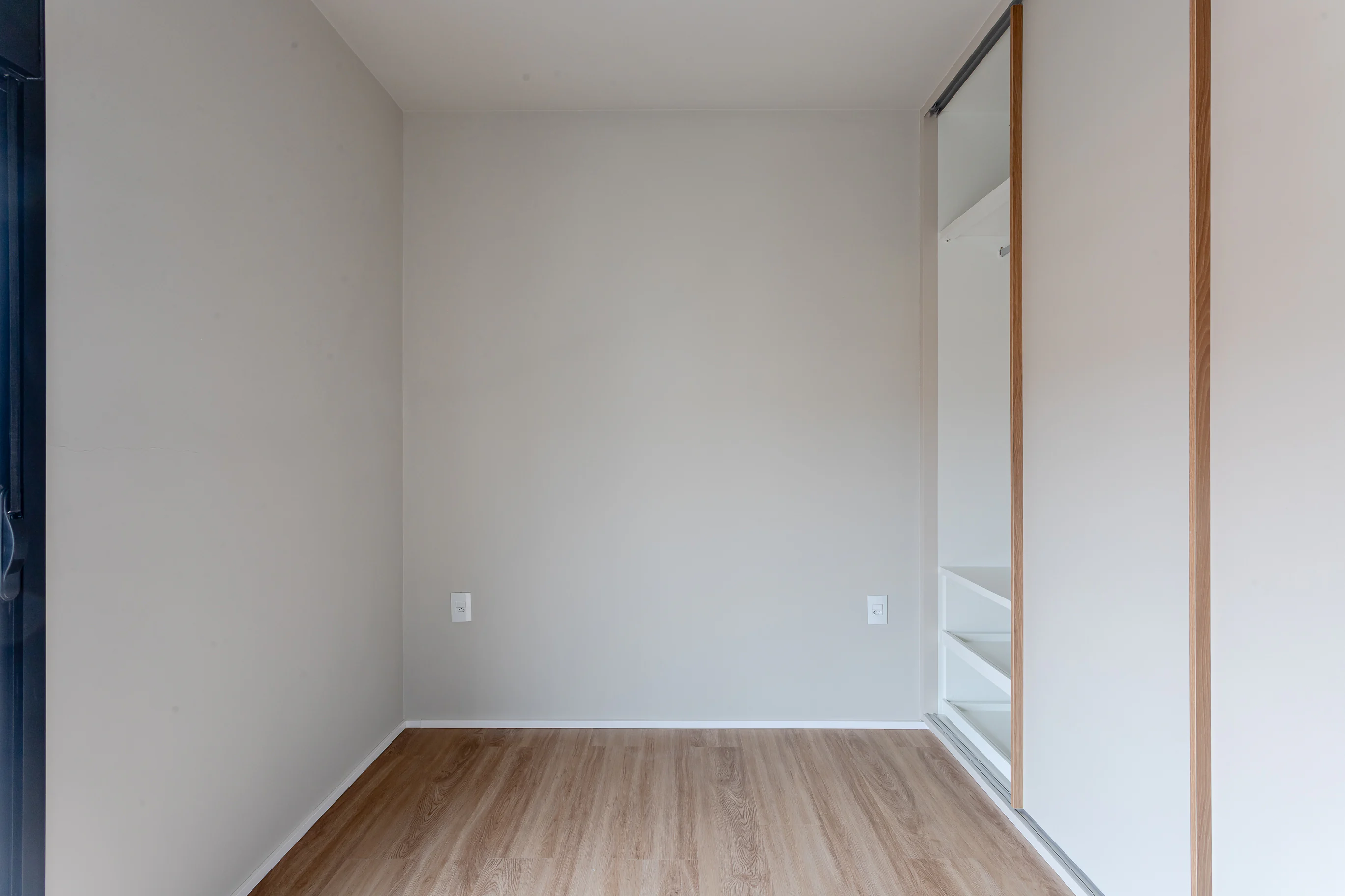 Ambiente interno da cobertura com piso amadeirado e porta de correr
