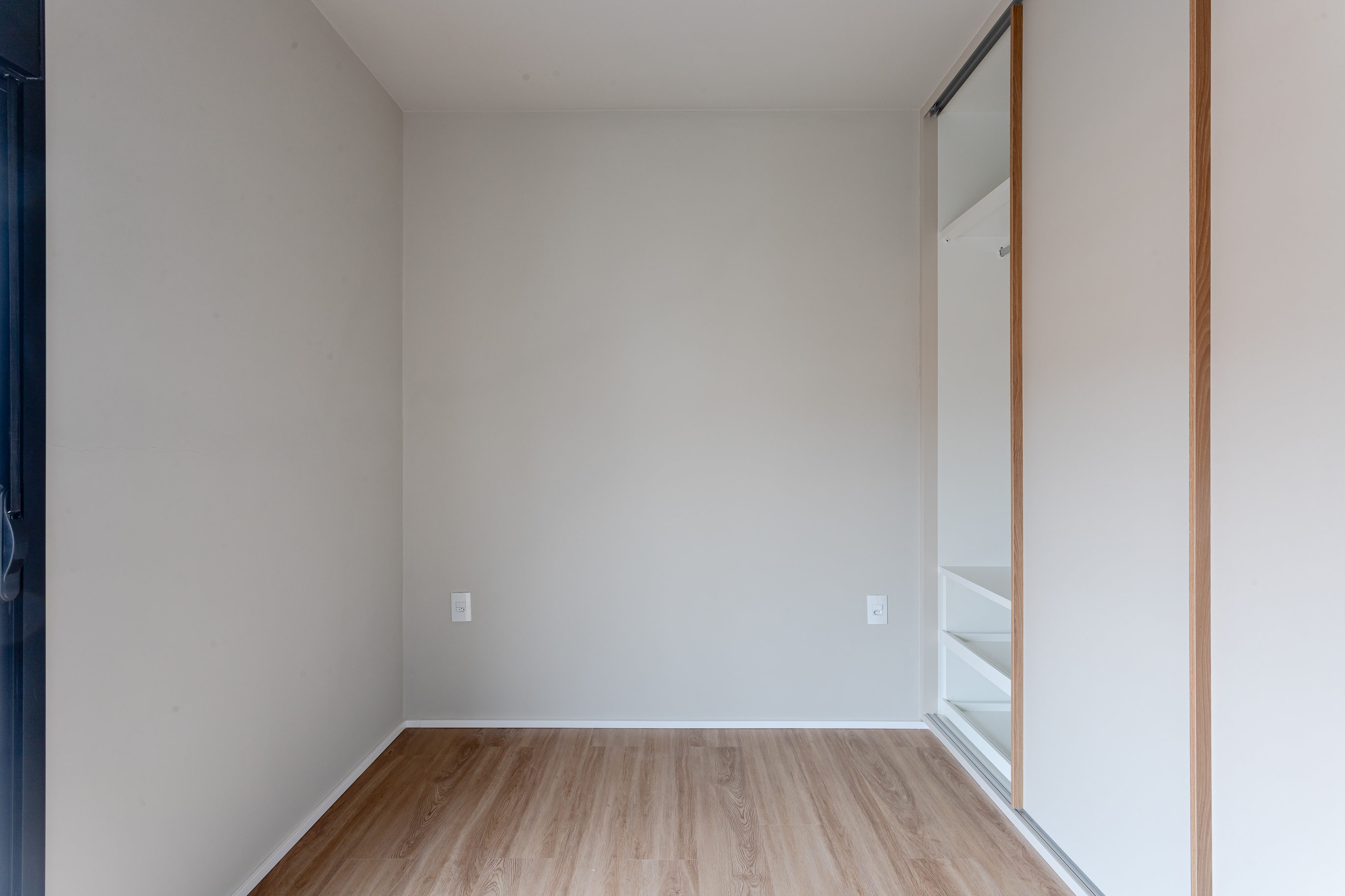 Ambiente interno da cobertura com piso amadeirado e porta de correr